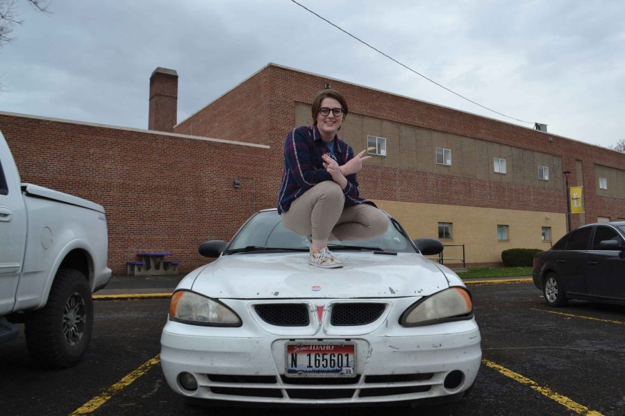 Dougherty mounts her white Pontiac, displaying her I voted sticker in LHS senior lot. Photo by Katie Swift. 
