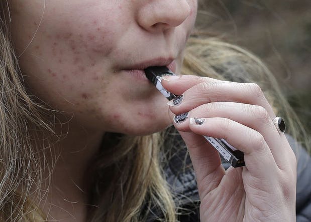 A teen in Massachusetts uses a Juul to vape on her school campus. Photo courtesy of StarTribune.com.  Right: A Juul advertised on an online shop. 