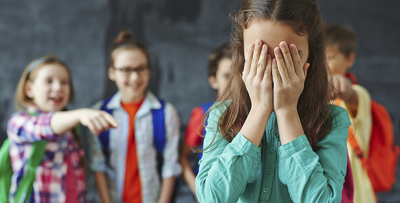 Girl cries as classmates bully her. Photo courtesy of Getty Images. 
