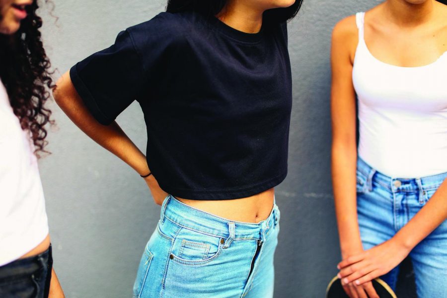 Teenage girls chat with each other while wearing crop tops considered too revealing for school. Photo courtesy of Getty Images. 