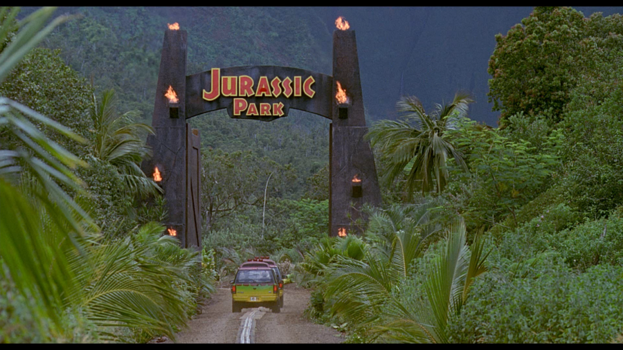 A car drives into the entrance of Jurassic Park.