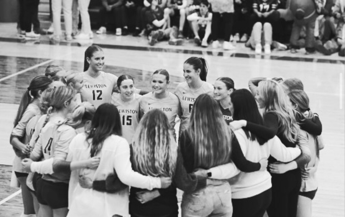 The LHS Varsity volleyball team celebrates in a huddle.